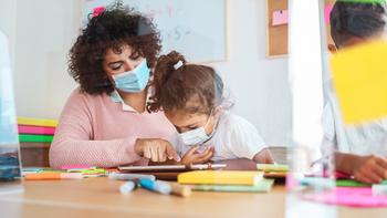 Kindergartenpädagogin mit Kind beide tragen eine Schutzmaske