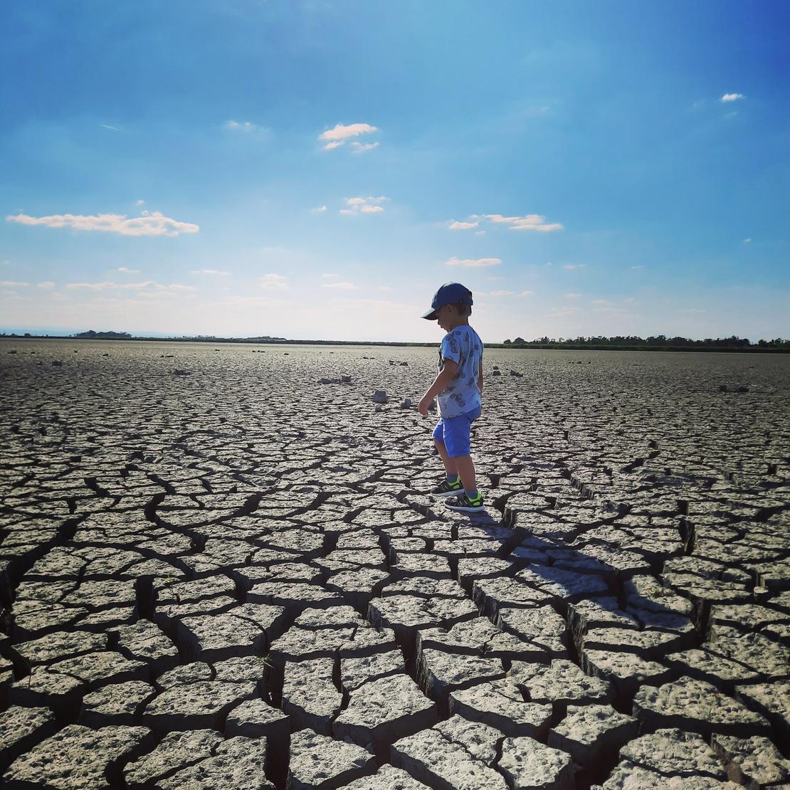 Ausgetrocknete Erde auf dem ein Kind spazieren geht