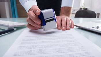 Thema Umstieg, eine Hand mit Stempel über ein Dokument