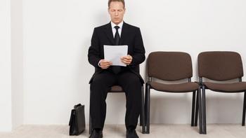 Wartezimmer in dem eine männliche Person, sitzend und in der Hand Dokumente festhält, wartet