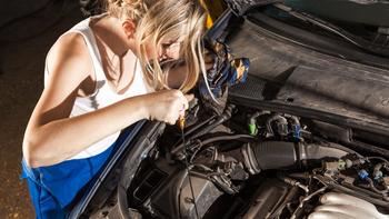 JUnge Frau repariert ein Auto