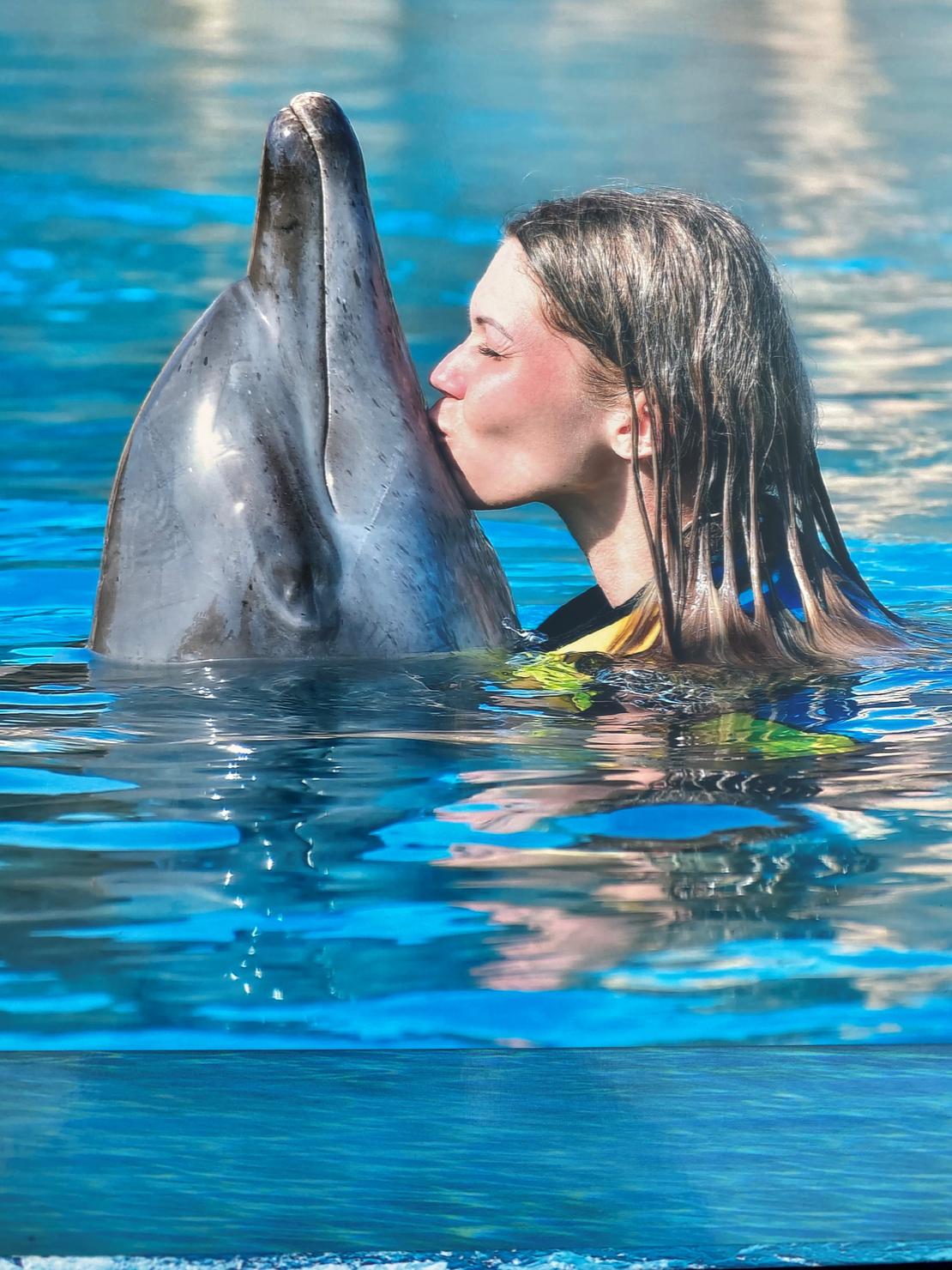Eine Frau küsst einen Delfin im Meer